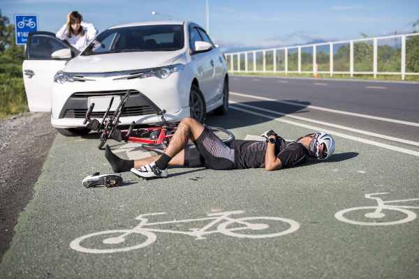 man hit by a car on his bike laying in the road