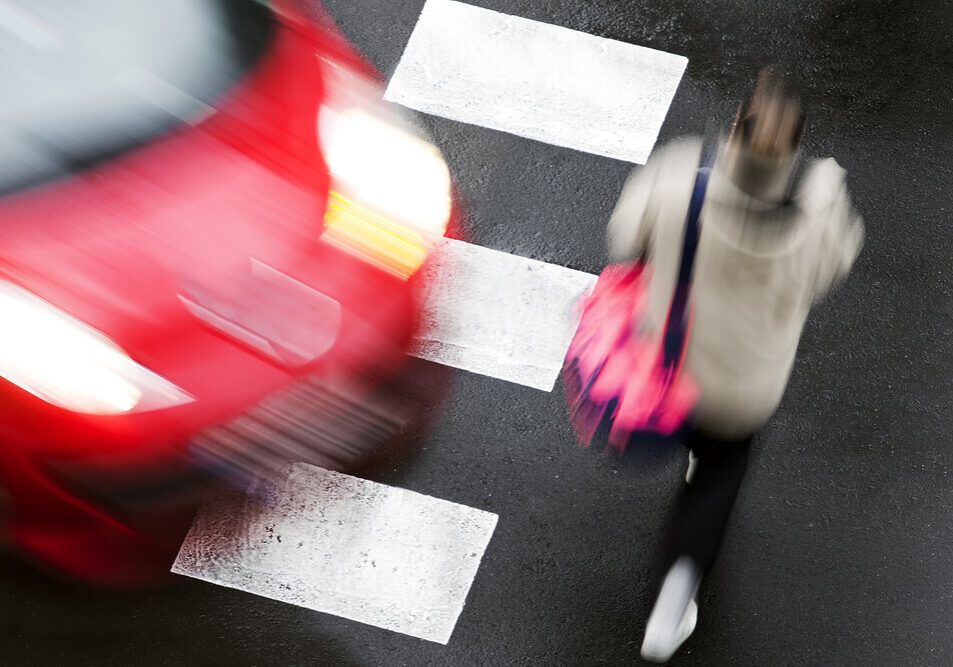 speeding car at a crosswalk while a woman is crossing