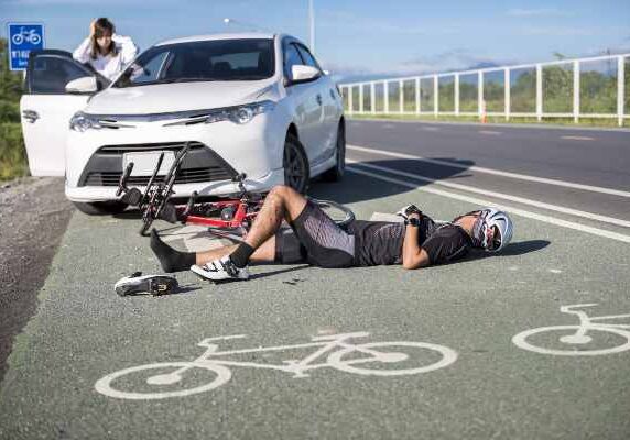 man hit by a car on his bike laying in the road